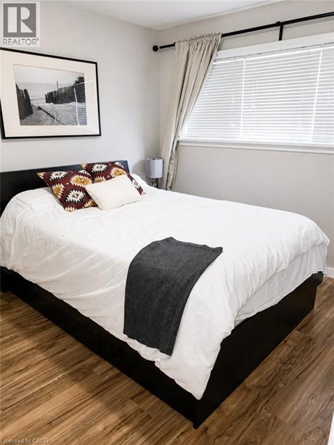 A bedroom with a white bed and a picture on the wall.