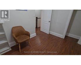 A brown chair sits in a room with white walls and a white door.