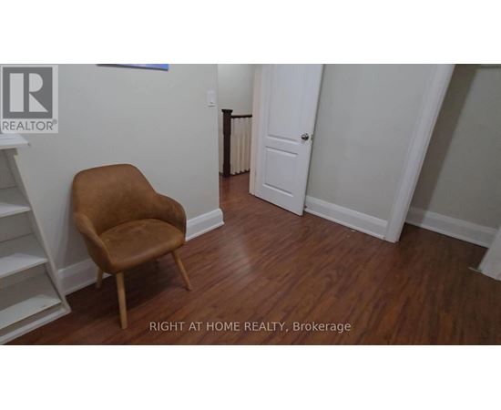 A brown chair sits in a room with white walls and a white door.