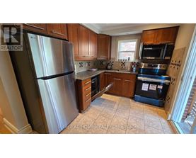 A kitchen with a stainless steel refrigerator and wooden cabinets.