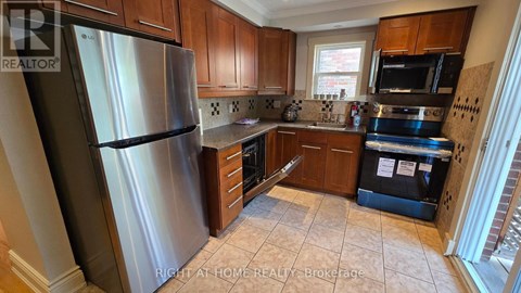 A kitchen with a stainless steel refrigerator and wooden cabinets.