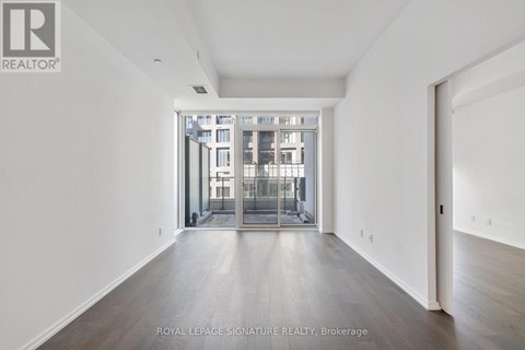 A spacious room with a view of a building through a glass door.