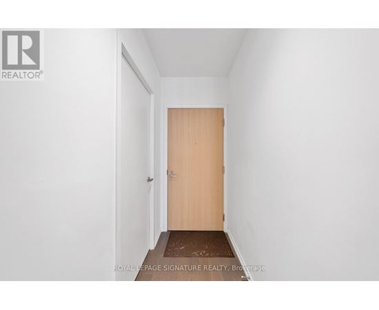 A hallway with a wooden door and a brown doormat.