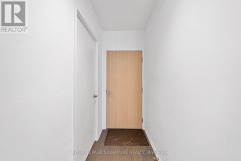A hallway with a wooden door and a brown doormat.