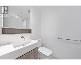 A white bathroom with a sink, mirror, toilet and a towel rack.