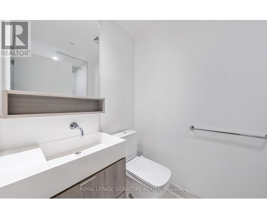 A white bathroom with a sink, mirror, toilet and a towel rack.