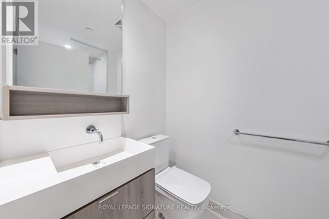 A white bathroom with a sink, mirror, toilet and a towel rack.