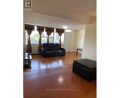 A living room with a black sofa and a wooden floor.