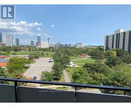 A view from a balcony overlooking a parking lot and buildings.