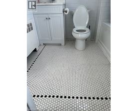 A white toilet in a bathroom with a white cabinet and a white bathtub.