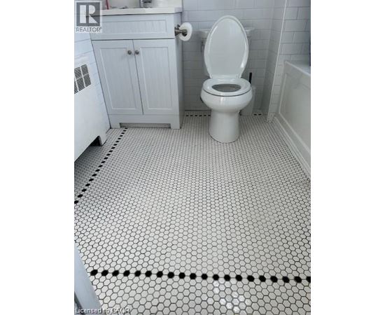A white toilet in a bathroom with a white cabinet and a white bathtub.