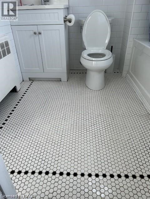 A white toilet in a bathroom with a white cabinet and a white bathtub.