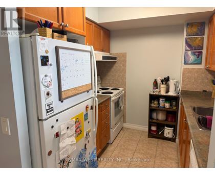 A white fridge with a calendar magnet on it in a kitchen.