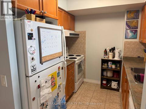 A white fridge with a calendar magnet on it in a kitchen.