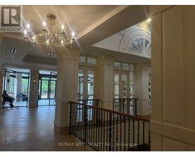 A chandelier hangs from the ceiling in a spacious lobby.
