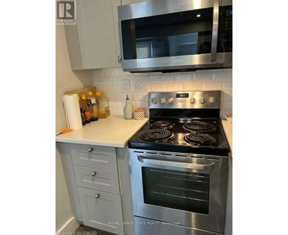 A stainless steel oven with four burners is in a kitchen.