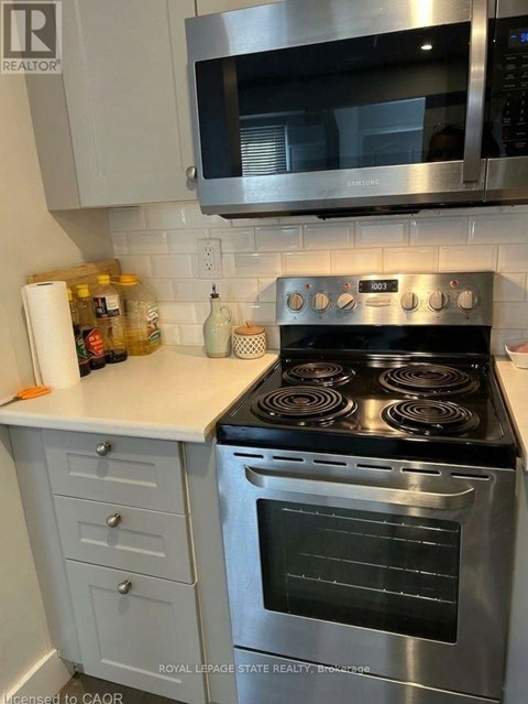 A stainless steel oven with four burners is in a kitchen.