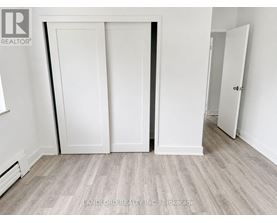 A room with white walls and a grey floor with a white door.