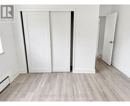 A room with white walls and a grey floor with a white door.