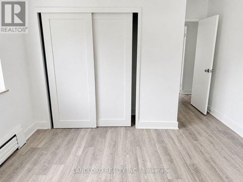 A room with white walls and a grey floor with a white door.