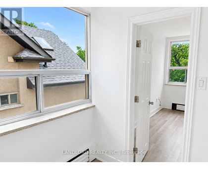 A room with a white door and a window showing a house and trees outside.