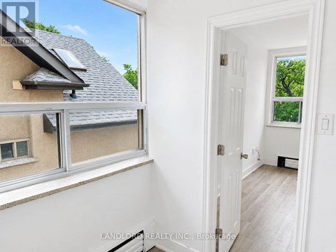 A room with a white door and a window showing a house and trees outside.