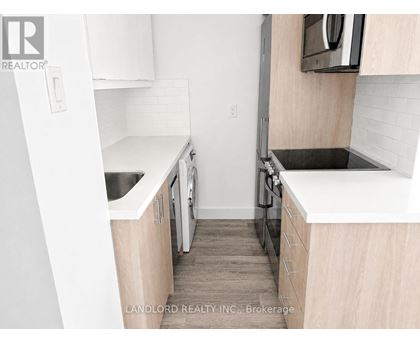A small kitchen with white cabinets and a black stove top.