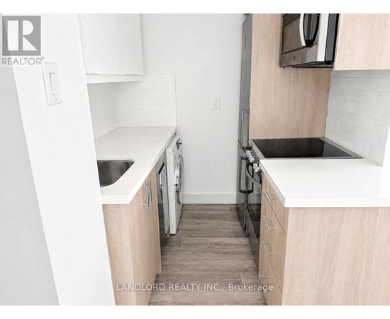 A small kitchen with white cabinets and a black stove top.