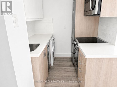 A small kitchen with white cabinets and a black stove top.