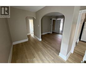 A spacious room with wooden flooring and white walls.