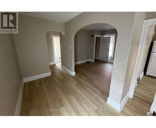 A spacious room with wooden flooring and white walls.