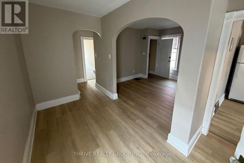 A spacious room with wooden flooring and white walls.
