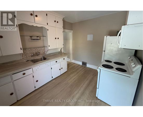 A kitchen with white cabinets and a white stove top oven.