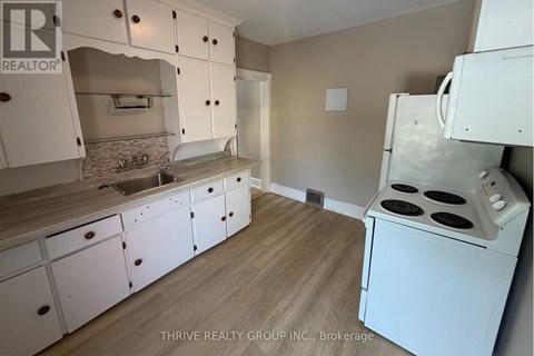 A kitchen with white cabinets and a white stove top oven.