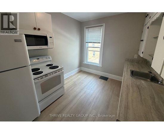 A kitchen with white appliances and a window.