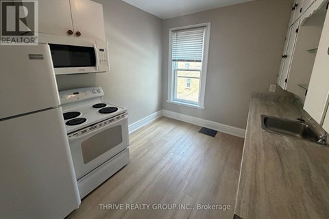 A kitchen with white appliances and a window.