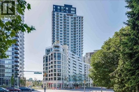 A tall building with the sign REASON on it stands in front of other buildings.