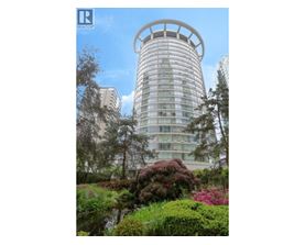 A tall building with a circular top is surrounded by greenery.