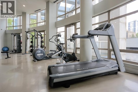 A treadmill is in the middle of a spacious room with other exercise equipment.