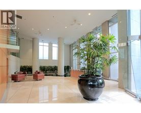 A large black pot with a green plant in it sits in the middle of a white tiled floor.