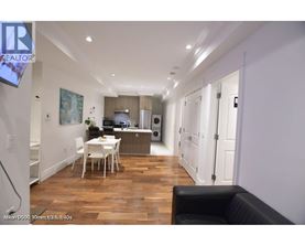 A well-lit, spacious kitchen and dining area with a black leather sofa.