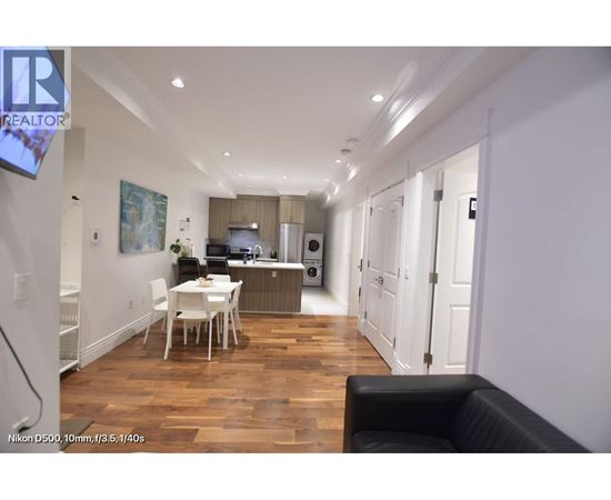 A well-lit, spacious kitchen and dining area with a black leather sofa.