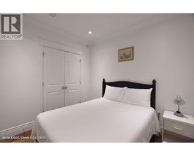 A bedroom with a white bed and a small nightstand with a lamp.