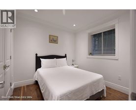A bedroom with a bed, nightstand, and window.