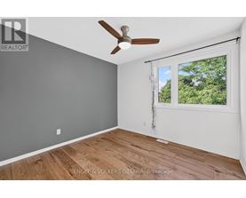 A room with a ceiling fan and a window showing trees outside.