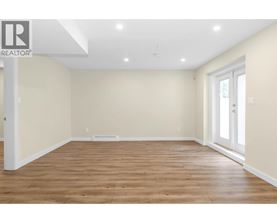 A spacious room with wooden flooring and white walls.