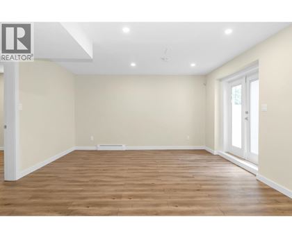 A spacious room with wooden flooring and white walls.