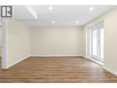 A spacious room with wooden flooring and white walls.