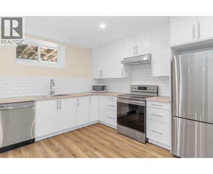 A modern kitchen with white cabinets and stainless steel appliances.