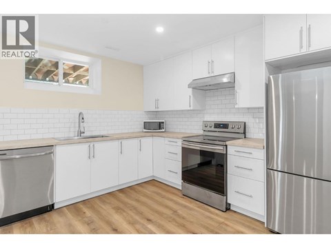 A modern kitchen with white cabinets and stainless steel appliances.